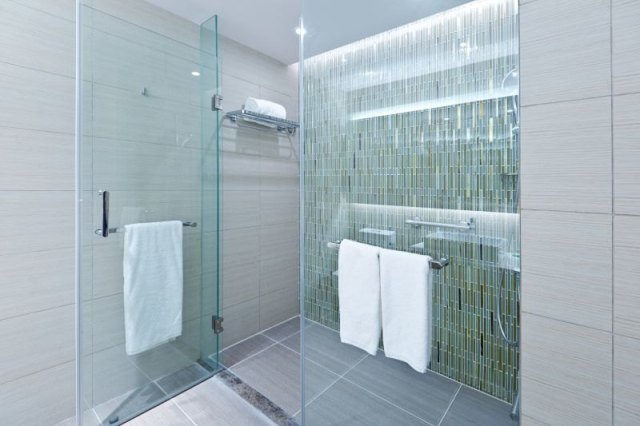 Completed shower installation with coordinated fixtures, shelving, and enclosure